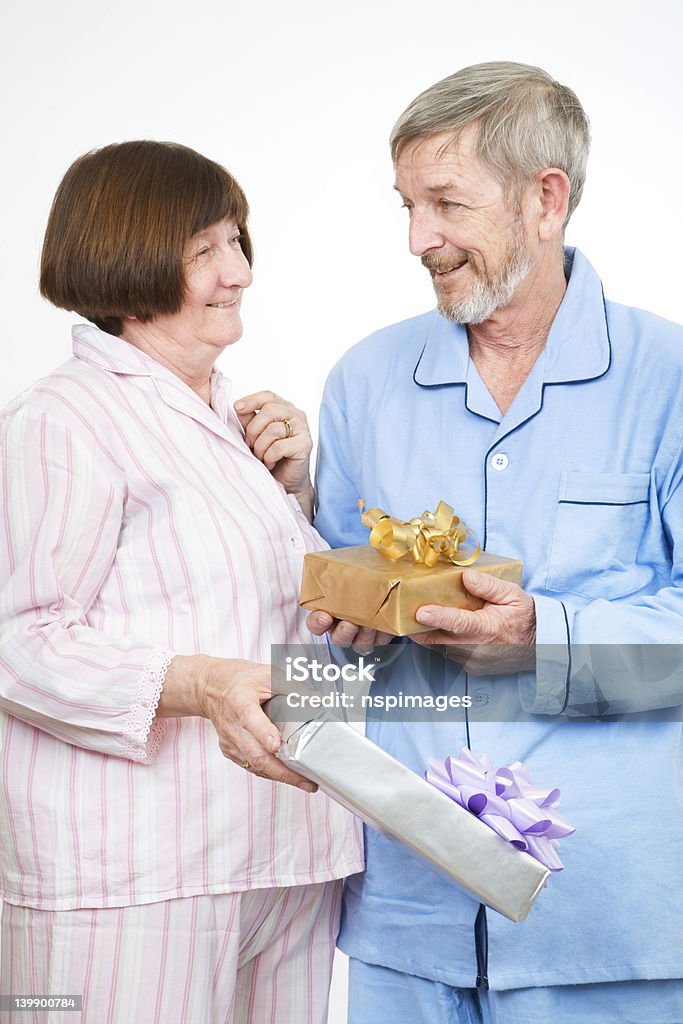 In pyjamas opening presents Senior couple 7, in pyjamas opening presents 50-59 Years Stock Photo