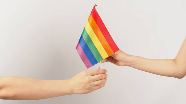 istock Two hands send and recive a rainbow flag on white background. LGBT CONCEPT. 1399008592