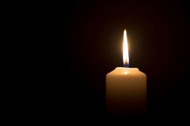 크리스마스, 장례식 또는 추도식을 위해 교회 테이블에 검은 색 또는 어두운 배경에 흰색 촛불에 빛나는 하나의 불타는 촛불 이나 빛 - candlestick holder single object zen like decoration 뉴스 사진 이미지