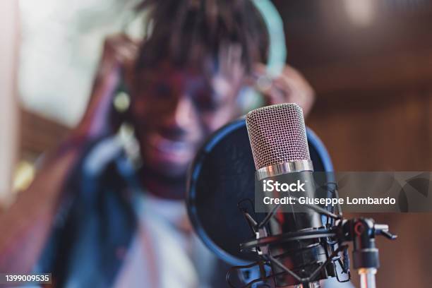 Condenser Microphone With Antipop In Front Of The Blurred Face Of An African Guy Singing Or Talking Live Technology Concept Of Young People Creating Contents And Casting Online Stock Photo - Download Image Now