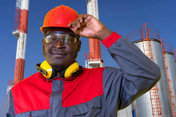 работник нефтеперерабатывающего завода в средствах индивидуальной защиты смотрит в камеру - нефтяник стоковые фото и изображения