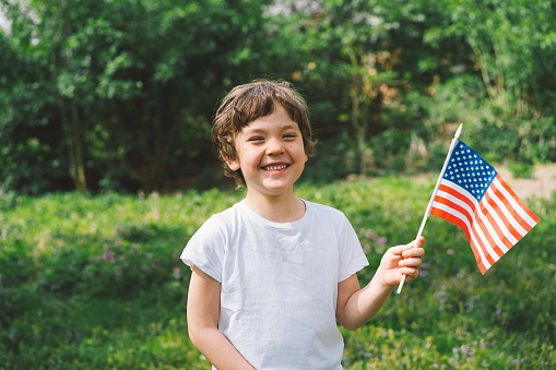 Happy little patriotic boy holding American flag. USA celebrate 4th of July. Happy independence day