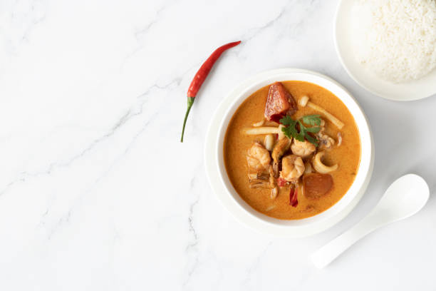 zuppa tom yum kung o con gamberi, peperoncino, riso al gelsomino e cucchiaio asiatico in un piatto bianco su sfondo di marmo. vista dall'alto, spazio di copia. - tom tom yum meal soup foto e immagini stock