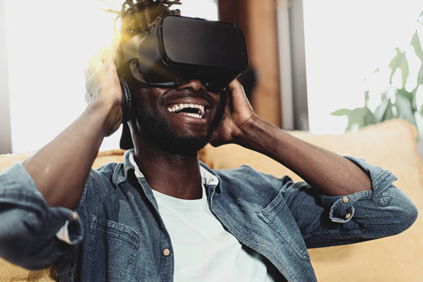 istock Young African man with 3D headset goggles reacting to 360 vr metaverse experience smiling carefree - lifestyle concept with young people having fun using new technologies 1399011002