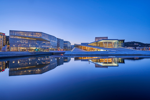Oslo, Norway – April 14, 2022: Oslo's Bjorvika (Inner Harbor) during sunrise with the calm water reflecting the famous Oslo Opera House.