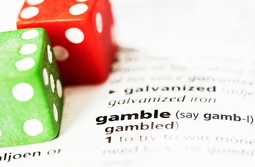 Brightly colored red and green dice resting on the page of a dictionary defining the word 