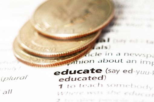Definición del diccionario de la palabra Educar, con monedas estadounidenses que representan el costo, los préstamos o la deuda estudiantil photo