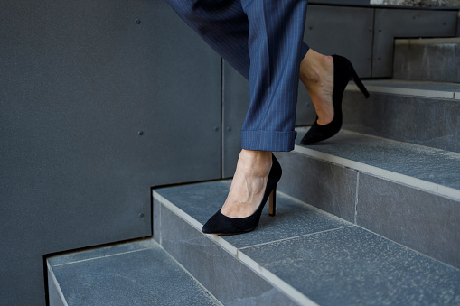 Close-up view of modern business woman legs walking down the stairs of business center building