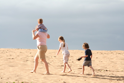 A mother and her three children walking on the beach.