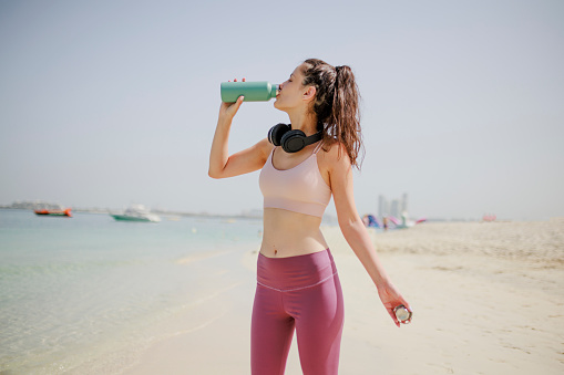 Fit woman drinking water on beach