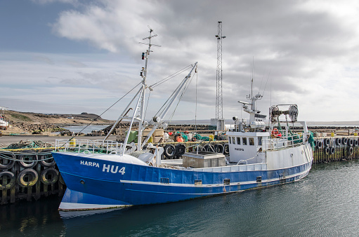 Hvammstangi, Iceland, May 1, 2022: blue and white fishing boat in the town's harbour on a sunny day