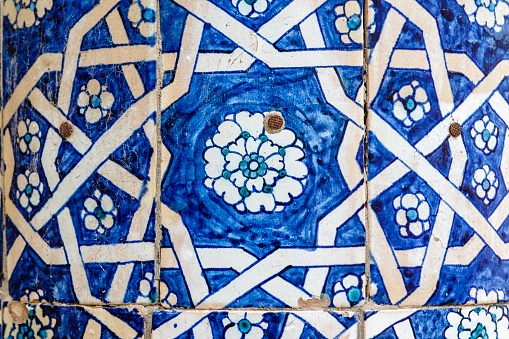 Close up of hand painted blue tiles with a flower motif on the facade of a madrassa in Khiva, Uzbekistan, Central Asia