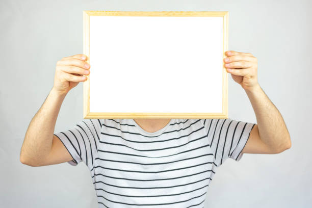 istock Young man holding cork pinboard in front of his face with five pinned paper, copy space, isolated on white background, paper area for text on wooden cork board, banner idea, 1399018452
