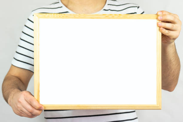 istock Young man holding wooden frame with blank area, copy space, isolated on white background, paper area for text on wooden pinboard, banner idea, message text concept 1399018470
