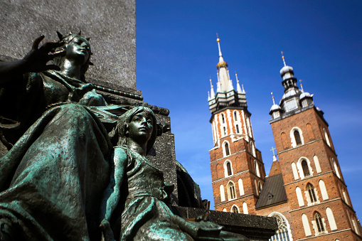 St. Mary's Basilica and detail of the Adam Mickiewicz Monument (designed by Teodor Rygier and built in 1898) on Main Market Square in Krakow, Poland.