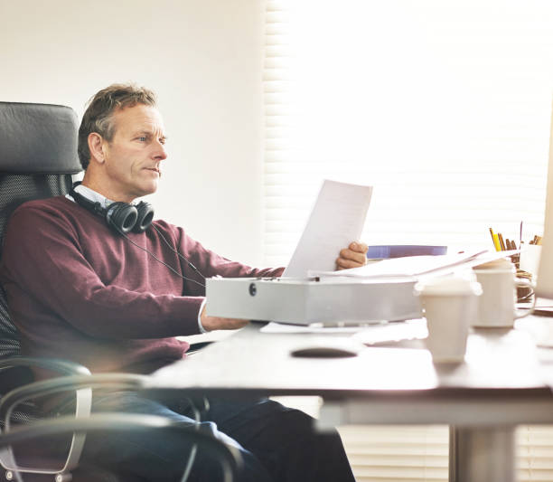 istock A businessman analysing paperwork in a modern office. A mature male executive going over a business document at his desk 1399018756