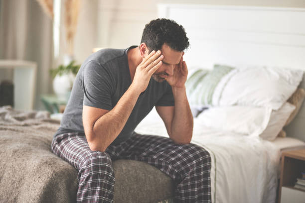 istock A man feeling stressed and suffering from a headache in bed at home. A mature guy looking unhappy, feeling sick in his bedroom during the morning 1399020405