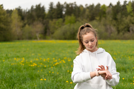 Teenage girl  looking at a smart watch while jogging in the park