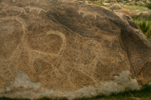 petroglyphs depicting an ancient hunt at Issyk-Kul  lake in the place red Cholpan-Ata on the stone. There many many stones