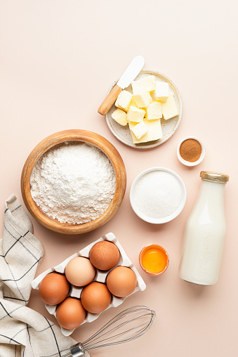 Baking ingredients for cakes bread cookies or pastry on beige background. Top view vertical orientation.