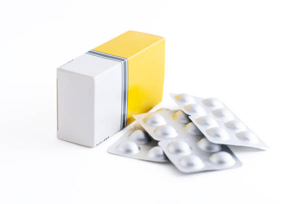 Heap of blister packs of pills and one blank cardboard box on white background stock photo