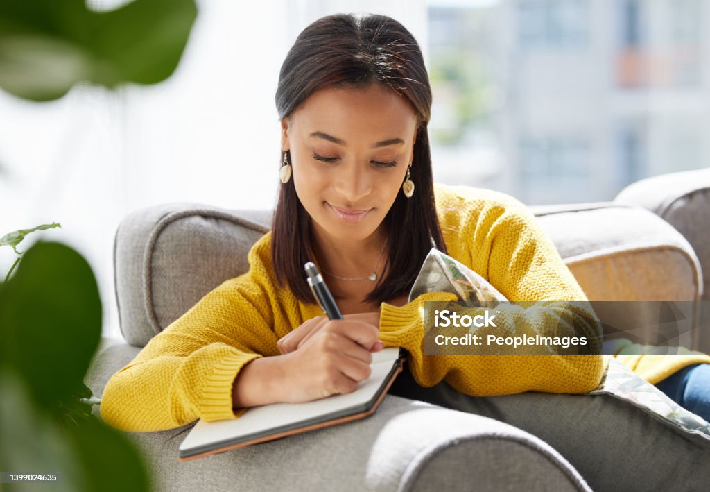 Shot of a young woman writing in a diary at home Thoughts on paper Diary Stock Photo