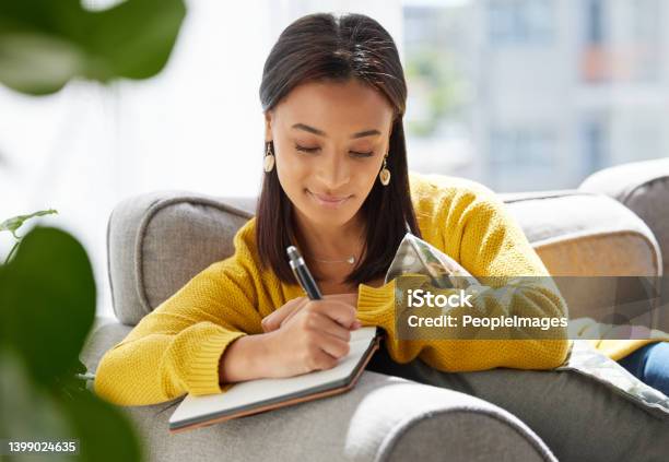 Shot Of A Young Woman Writing In A Diary At Home Stock Photo - Download Image Now - Diary, Writing - Activity, Note Pad