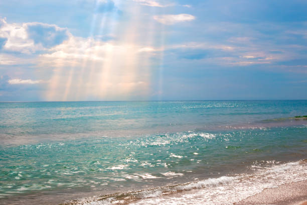 Blue sea and dark sky with sun rays on a summer day. Seascape.