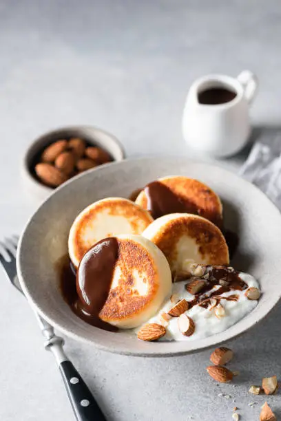 Syrniki, curd cheese or cottage cheese fritters served with chocolate sauce, yogurt and almonds. Gourmet sweet breakfast