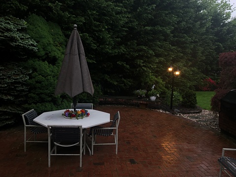 Picturesque evening setting after a rain storm. Wet grounds, lush greenery, warm yellow lights from lantern light post. Rain calls for great photos!