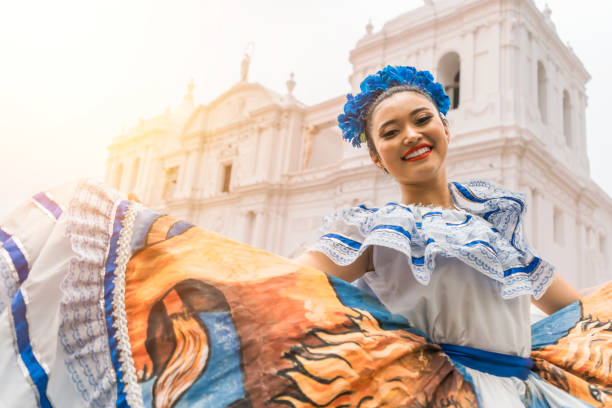 ballerino folcloristico nicaraguense sorridente e che guarda la telecamera fuori dalla chiesa cattedrale nel parco centrale della città di leon. la donna indossa l'abito tipico dell'america centrale e simile ai paesi del sud america - tradizione foto e immagini stock