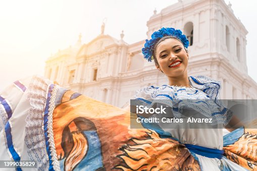 istock Nicaraguan folklore dancer smiling and looking at the camera outside the cathedral church in the central park of the city of Leon. The woman wears the typical dress of Central America and similar to countries of South America 1399035829