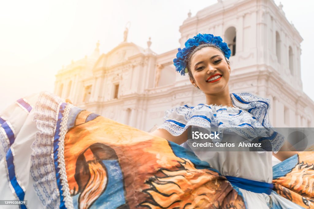 Nicaraguan folklore dancer smiling and looking at the camera outside the cathedral church in the central park of the city of Leon. The woman wears the typical dress of Central America and similar to countries of South America Nicaraguan folklore dancer smiling and looking at the camera outside the cathedral church in the central park of the city of Leon. The woman wears the typical dress of Central America and similar to countries of South America and Mexico. Latin American and Hispanic Ethnicity Stock Photo