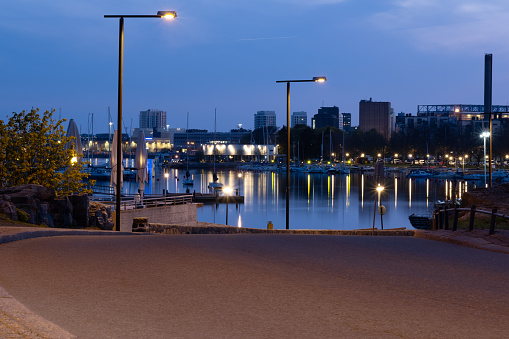 Helsinki / Finland - MAY 22, 2022: View of a shore promenade with calm sea and sleeping city in the background.