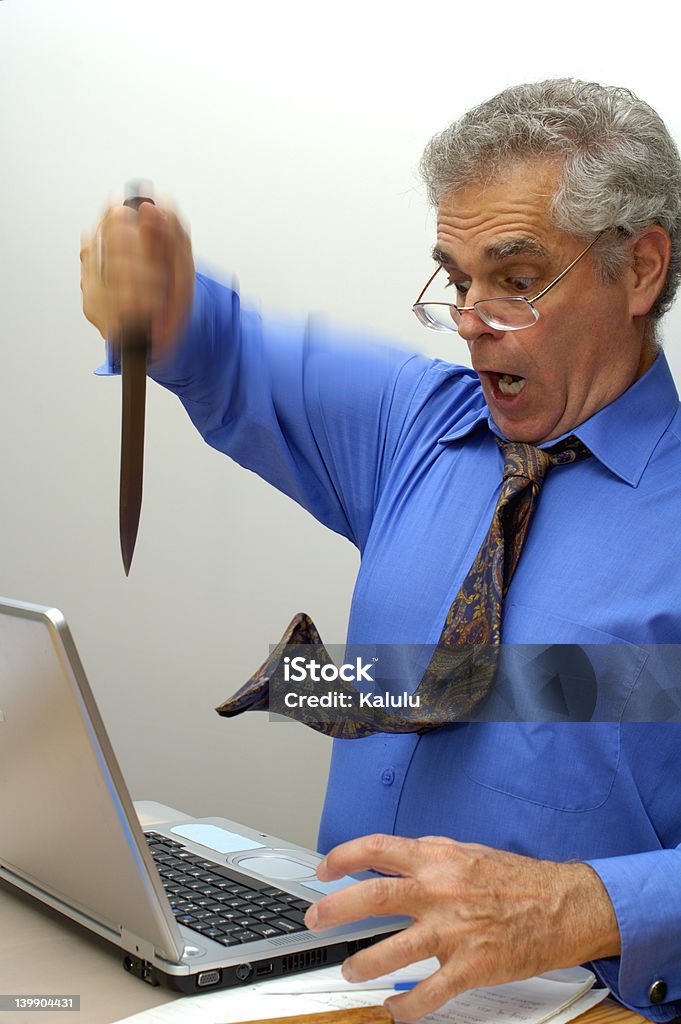 Take that! An older businessman fed up with his laptop, stabs it with a knife. Adult Stock Photo