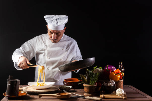 istock Male chef in white uniform prepares spaghetti with vegetables on the dish 1399044371