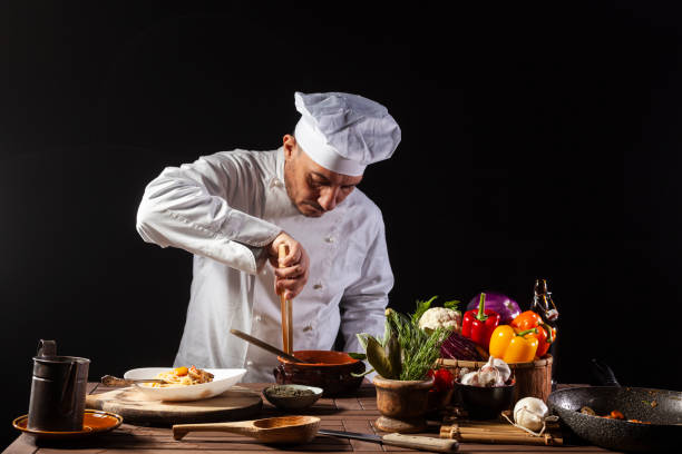 istock Male chef in white uniform prepares spaghetti with vegetables on the dish 1399044378
