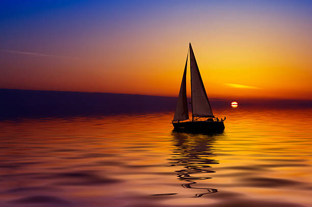 Sailboat on calm water during colorful sunset stock photo