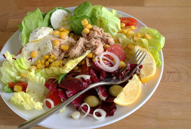 Healthy food. Fresh salad with tuna and mozzarella cheese on a plate. Mediterranean food. Directly above.