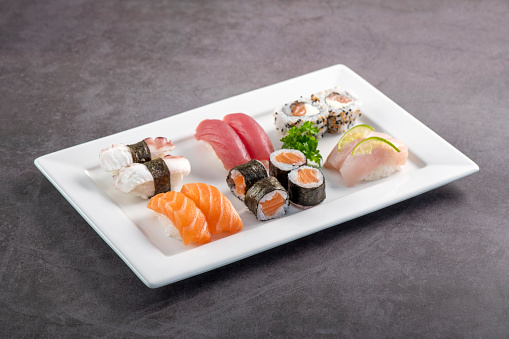 Sushi mix on white plate. Studio shoot isolated on slate background. Salmon, tuna, octopus and white fish different kinds of sushi. Oriental food on Brazilian way!