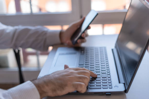 istock Man typing on a laptop and checking the mobile phone while teleworking. 1399048297