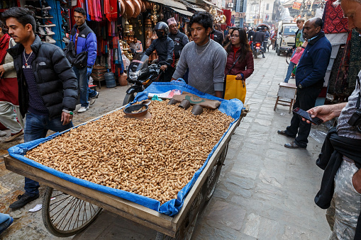 Kathmandu, Nepal - November 25, 2016: A local merchant with a cart of nuts on the street in Kathmandu.