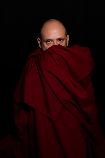 Man covered with red cloth against a black background. Salvador, Bahia, Brazil.