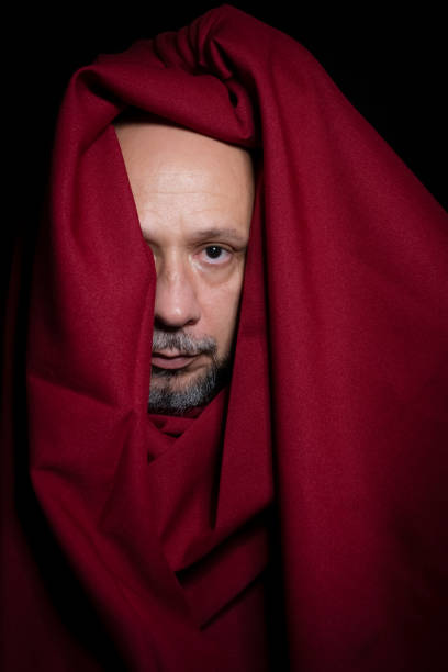 Man covered with red cloth against a black background. Salvador, Bahia, Brazil.