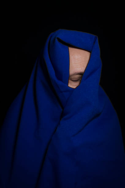 istock Man covered with blue cloth against a black background. 1399051508