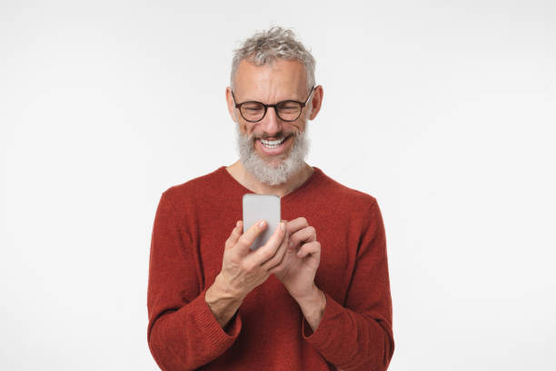 Happy mature middle-aged man freelancer using smart phone cellphone for online texting, social media, e-banking, remote work isolated in white background