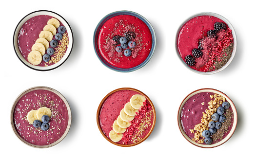various healthy breakfast smoothie bowls of banana and berries isolated on white background, top view