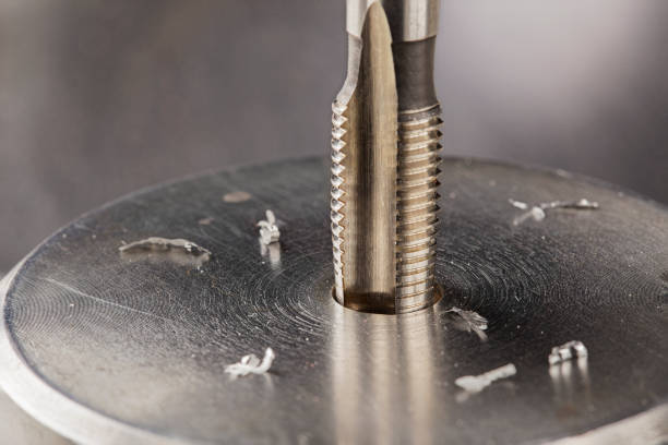 Thread tap drill steel billet with drill bit on background. Working cutter.