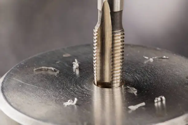 Photo of Thread tap drill steel billet with drill bit on background. Working cutter.