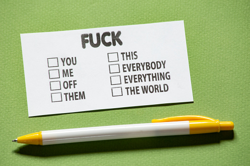 A Card with the option fuck - you, me, off, them, this, everybody, everything, world with a check box on a green background. with a yellow and white pen next to it.